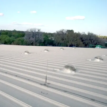 Several tubular skylight domes installed on a metal commercial roof